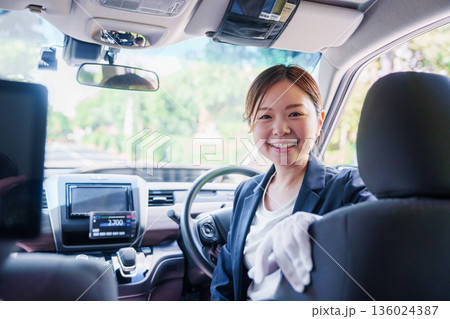 笑顔で運転をするタクシードライバーの女性 136024387