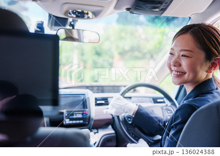 笑顔で運転をするタクシードライバーの女性 136024388