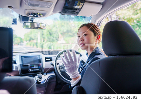 笑顔で運転をするタクシードライバーの女性 笑顔で運転をするタクシードライバーの女性 136024392