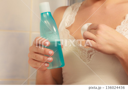 Woman cleaning neckline with cotton swab pad 136024436