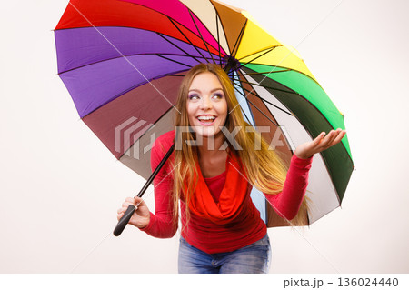 Woman standing under multicolored umbrella Woman standing under multicolored umbrella 136024440