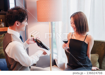 ホテルのルームサービスで女性にワインを提供する男性スタッフ ホテルのルームサービスで女性にワインを提供する男性スタッフ 136024708