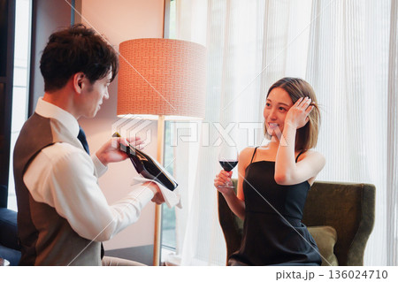 ホテルのルームサービスで女性にワインを提供する男性スタッフ 136024710