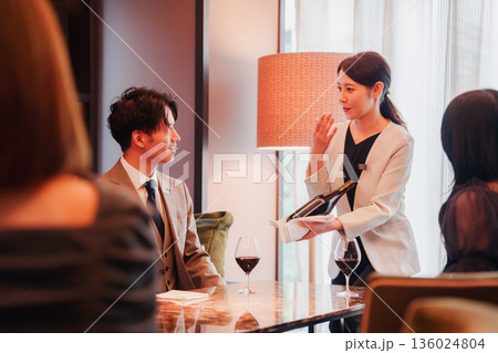 ワインをお客様におすすめをする女性のスタッフ 136024804