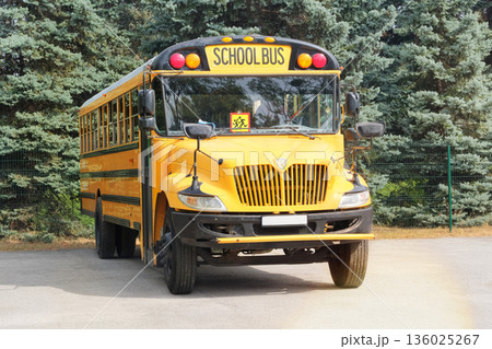 School bus in yard near school. School shuttle and student transportation. Public transportation. School bus in yard near school. School shuttle and student transportation. Public transportation. 136025267