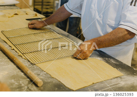 Chef male hands working with dough on a table in a bakery. 136025393