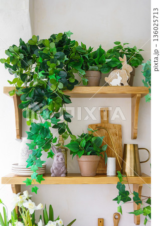 Easter decor with green plants, bunny figurine and spring home interior details on wooden shelf Easter decor with green plants, bunny figurine and spring home interior details on wooden shelf 136025713