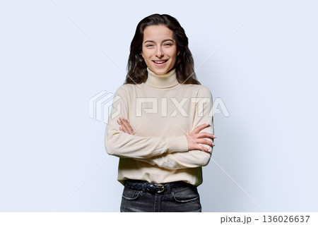 Beautiful young woman with crossed arms looking at camera on white background Beautiful young woman with crossed arms looking at camera on white background 136026637
