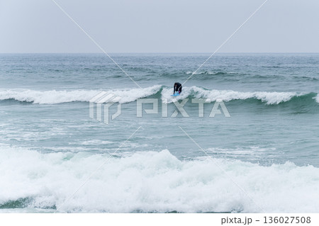 Surfer girl riding a wave 136027508