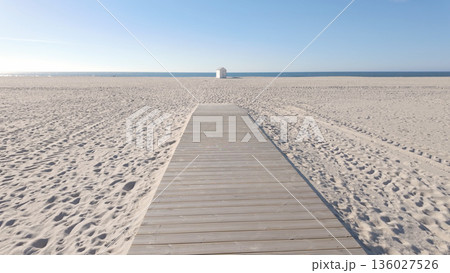 A wide wooden walkway stretches across a vast, pristine beach A wide wooden walkway stretches across a vast, pristine beach 136027526