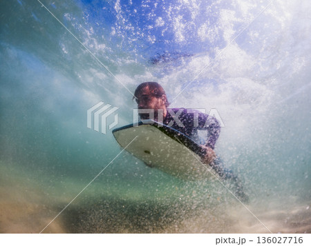 Bodyboarder duck diving a wave 136027716