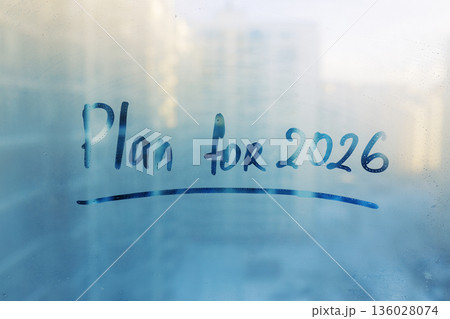 Lettering words Plan for 2026 on foggy glass window on blue sunset background Lettering words Plan for 2026 on foggy glass window on blue sunset background 136028074