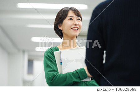 同僚と立ち話をする若いキャリアウーマン 同僚と立ち話をする若いキャリアウーマン 136029069