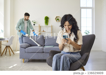 Happy woman using smartphone, looking in secret at screen to read hidden messages 136029809