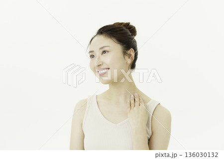 白背景のタンクトップを着て首筋を触る若い日本人女性 白背景のタンクトップを着て首筋を触る若い日本人女性 136030132