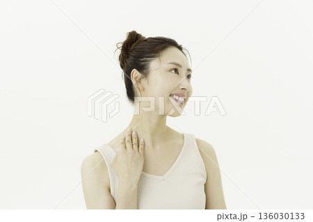 白背景のタンクトップを着て首筋を触る若い日本人女性 136030133