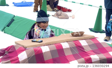 ソリこたつを楽しむ少女 136030294