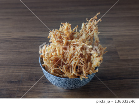Crispy fried enoki, also known as deep-fried needle mushrooms, are coated with spiced flour and deep-fried to a golden-brown, crunchy texture; they are served in a blue and white patterned bowl Crispy fried enoki, also known as deep-fried needle mushrooms, are coated with spiced flour and deep-fried to a golden-brown, crunchy texture; they are served in a blue and white patterned bowl 136032240