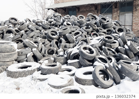 Old tires are stacked in a recycling yard located in a cold area showing the process of reusing rubber and reducing landfill waste. High quality photo 136032374