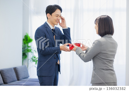 社内で男性にプレゼントを渡す女性 136032382