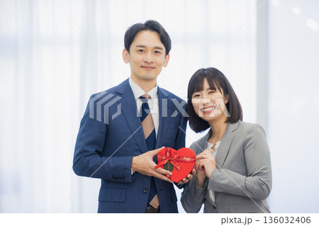 社内で男性にプレゼントを渡す女性  136032406
