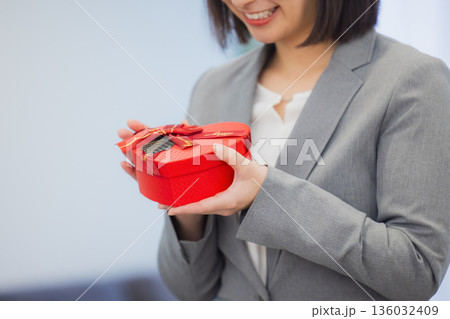 社内で男性にプレゼントを渡す女性  136032409
