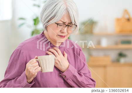 胸痛で苦しくて胸を抑えるシニア女性(誤嚥,むせる,嚥下機能) 胸痛で苦しくて胸を抑えるシニア女性(誤嚥,むせる,嚥下機能) 136032654