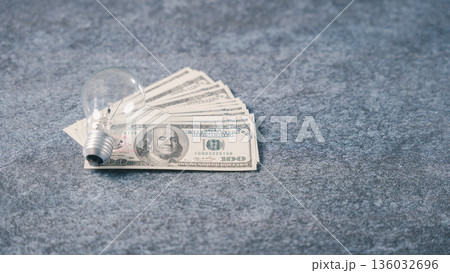 Bright light bulb lamp idea for business innovation, marketing concept sits on fan of hundred dollar bills over gray stone background surface for global market success and wealth Bright light bulb lamp idea for business innovation, marketing concept sits on fan of hundred dollar bills over gray stone background surface for global market success and wealth 136032696
