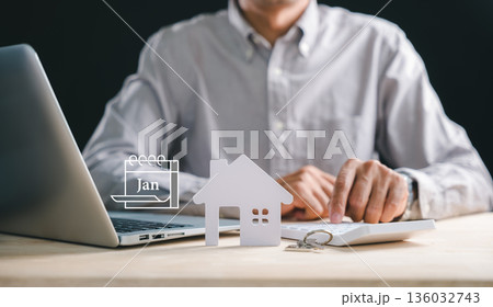 Financial planning for home investment involves man calculating money using calculator, property model, and laptop, displaying January calendar for future finance plan, showing mortgage loan Financial planning for home investment involves man calculating money using calculator, property model, and laptop, displaying January calendar for future finance plan, showing mortgage loan 136032743