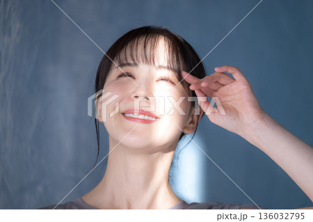 水色背景で日射しの中でポーズをとる女性 上半身アンニュイな眩しい表情 日焼け止めやuvなど紫外線のイ 水色背景で日射しの中でポーズをとる女性 上半身アンニュイな眩しい表情 日焼け止めやuvなど紫外線のイ 136032795