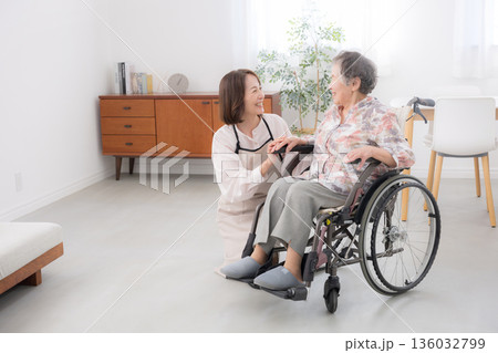 自宅で車椅子の母を介護をする様子　見つめ合う会話をする全身の広角	 136032799