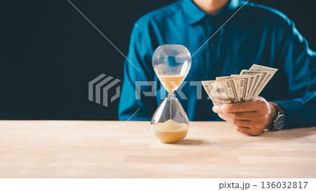 Money time hourglass, business investment finance and global economy concept, person holding banknotes illustrates saving deposit bank strategy for future world wealth Money time hourglass, business investment finance and global economy concept, person holding banknotes illustrates saving deposit bank strategy for future world wealth 136032817