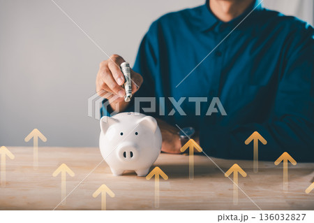 Global economy money bank piggy finance stock growth business concept, person puts cash into piggy bank to save and invest economic funds with rising arrows showing market profit Global economy money bank piggy finance stock growth business concept, person puts cash into piggy bank to save and invest economic funds with rising arrows showing market profit 136032827