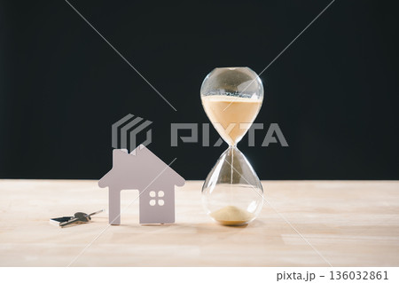 Hourglass with flowing sand, small model house, and keys symbolize real estate time constraint, mortgage loan deadline, or property buying selling temporary investment concept Hourglass with flowing sand, small model house, and keys symbolize real estate time constraint, mortgage loan deadline, or property buying selling temporary investment concept 136032861