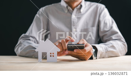 Exterior home property concept, man exploring new house options on smartphone for future real estate loan, digital search for modern estate investment plan on desk Exterior home property concept, man exploring new house options on smartphone for future real estate loan, digital search for modern estate investment plan on desk 136032871