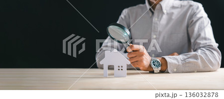 Man performs real estate appraisal, holding magnifying glass inspecting house property, conducting thorough home valuation, appraise search for investment planning, ensuring meticulous property 136032878