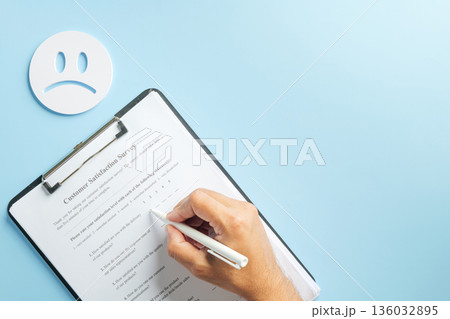 Customer survey form for feedback on clipboard, hand writing satisfaction review with pen, business checklist for data collection, sad face suggests negative experience evaluation Customer survey form for feedback on clipboard, hand writing satisfaction review with pen, business checklist for data collection, sad face suggests negative experience evaluation 136032895