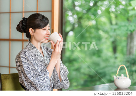 旅館の和室でお茶を飲む浴衣姿の若いアジア人女性 旅館の和室でお茶を飲む浴衣姿の若いアジア人女性 136033204