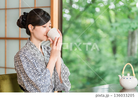 旅館の和室でお茶を飲む浴衣姿の若いアジア人女性 旅館の和室でお茶を飲む浴衣姿の若いアジア人女性 136033205