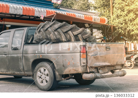 repair of agricultural tires and tires for special equipment. A large tire from a grader in the back of an old rusty pickup truck on Koh kho khao Island in Thailand. High quality photo repair of agricultural tires and tires for special equipment. A large tire from a grader in the back of an old rusty pickup truck on Koh kho khao Island in Thailand. High quality photo 136033312