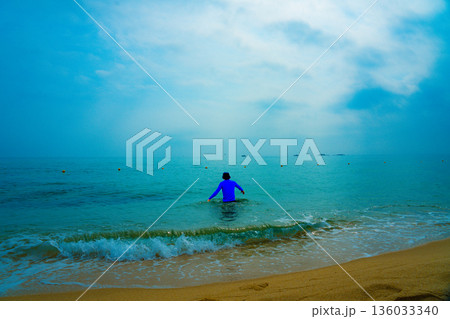 Asian man entering the sea Asian man entering the sea 136033340