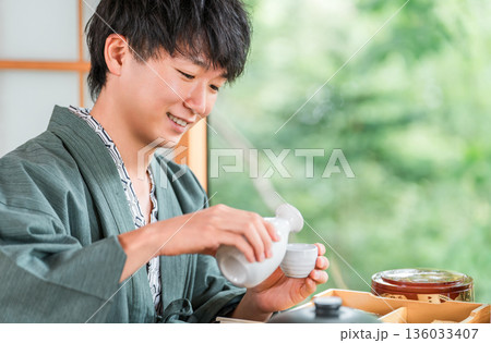 旅館で会席料理で日本酒を楽しむ若いアジア人男性(部屋食・懐石料理・御膳・贅沢) 旅館で会席料理で日本酒を楽しむ若いアジア人男性(部屋食・懐石料理・御膳・贅沢) 136033407