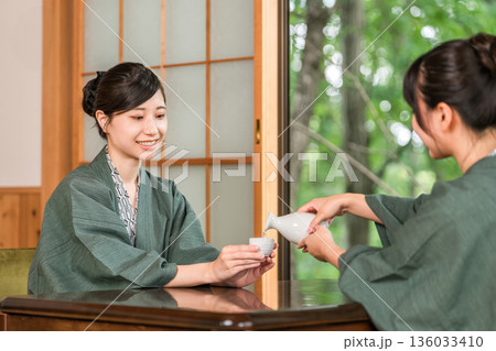 日本旅館の和室の縁側で浴衣姿で日本酒を飲む女性・友人 136033410