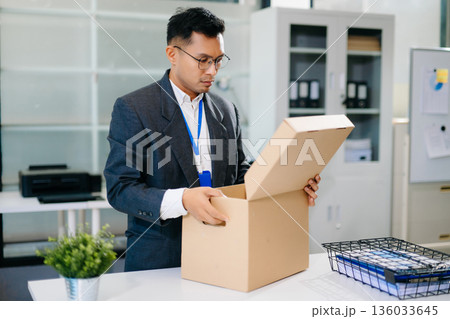 Sad businessman sitting in office with box and ID card after layoff, feeling exhausted and depressed from job loss and workplace stress. 136033645