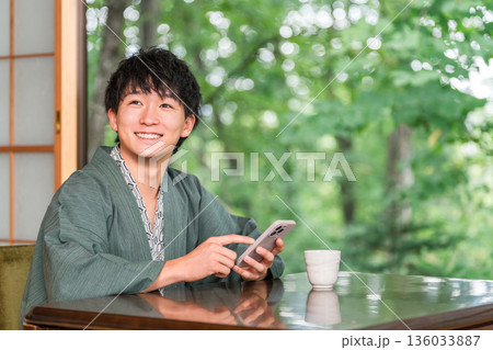 旅館の和室でスマホを見る浴衣姿の男性 136033887