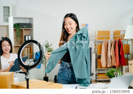 Fashion blogger concept, Young Asian women selling clothes on video streaming.Startup small business SME, using smartphone or tablet taking receive and checking Fashion blogger concept, Young Asian women selling clothes on video streaming.Startup small business SME, using smartphone or tablet taking receive and checking 136033909