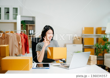 Young business owner woman prepare parcel box and standing check online orders for deliver to customer on tablet, laptop Shopping Online concept. Young business owner woman prepare parcel box and standing check online orders for deliver to customer on tablet, laptop Shopping Online concept. 136034357