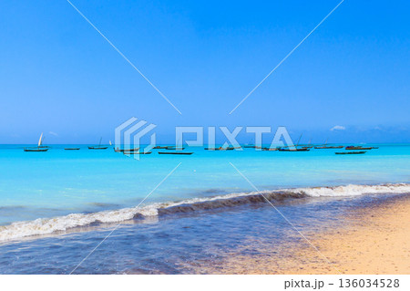 View of tropical sandy Nungwi beach and traditional wooden dhow boats in the Indian ocean on Zanzibar, Tanzania View of tropical sandy Nungwi beach and traditional wooden dhow boats in the Indian ocean on Zanzibar, Tanzania 136034528