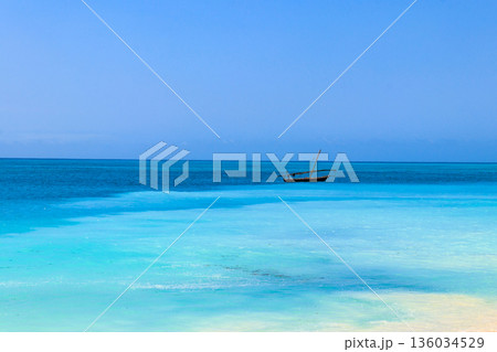 View of tropical sandy Nungwi beach and traditional wooden dhow boat in the Indian ocean on Zanzibar, Tanzania View of tropical sandy Nungwi beach and traditional wooden dhow boat in the Indian ocean on Zanzibar, Tanzania 136034529