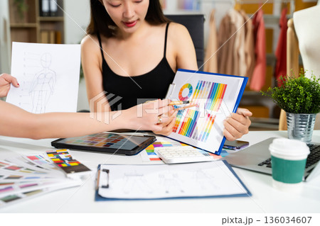 Fashion designers collaborating with color palettes, sketches, and digital tools in a studio. Creative design process, branding, textile planning 136034607